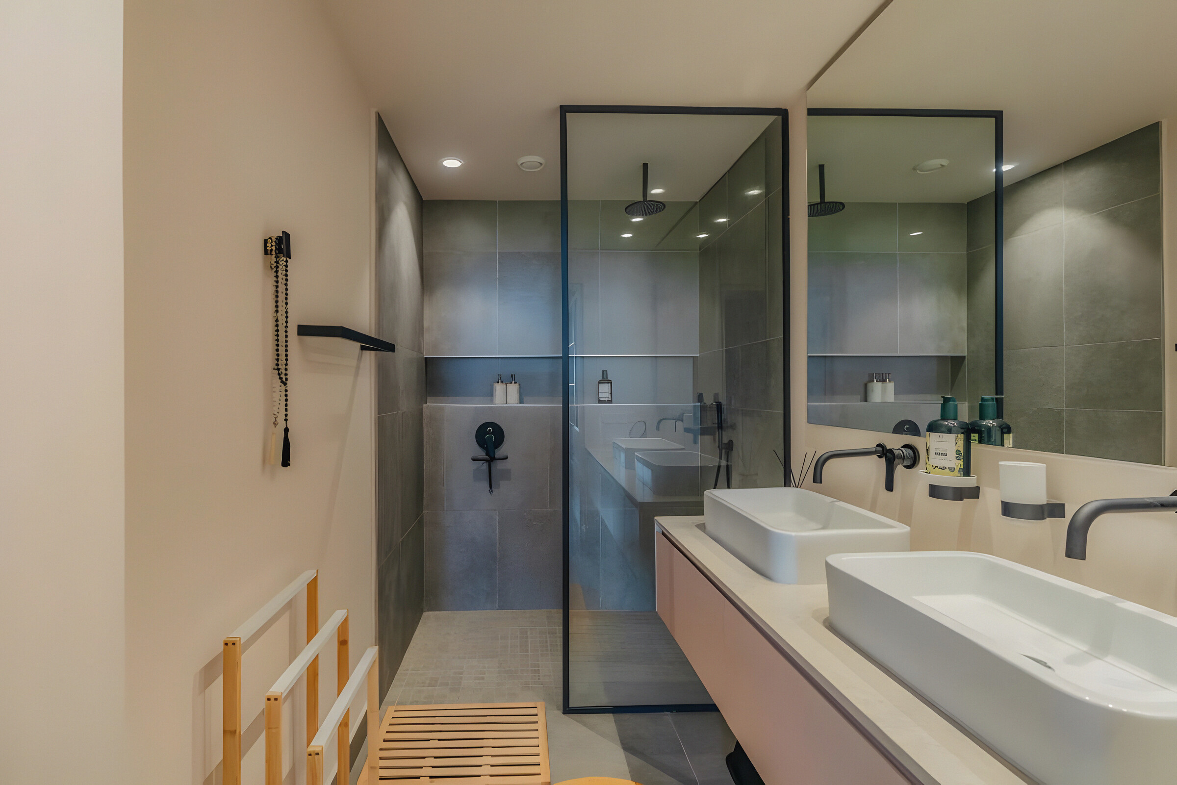 A bathroom with twin basins and a glazed walk-in rain shower